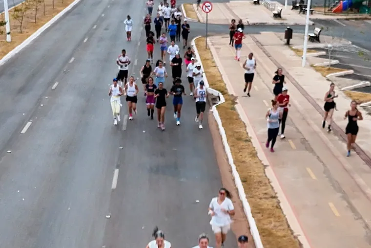 Dezenas de corredores espalhados pela avenida larga, vistos do alto pelo drone.
