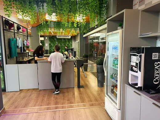 Área de conveniência com geladeira de bebidas e máquina de café.